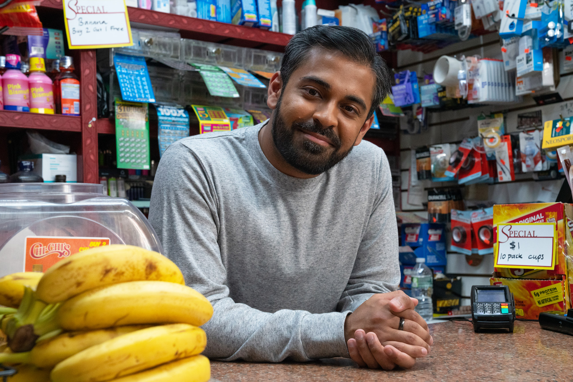 A shop keeper smiles from behind a counter