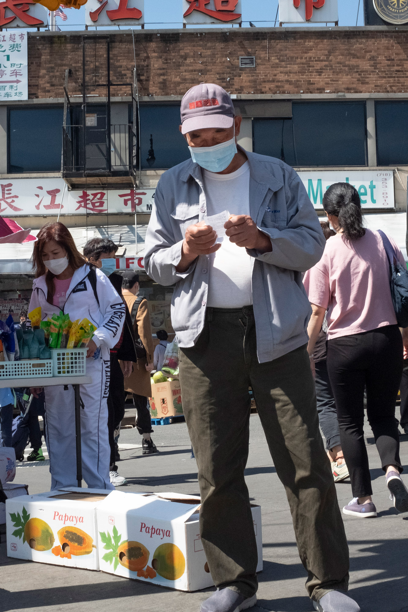 Man stops to read a note at a busy street market