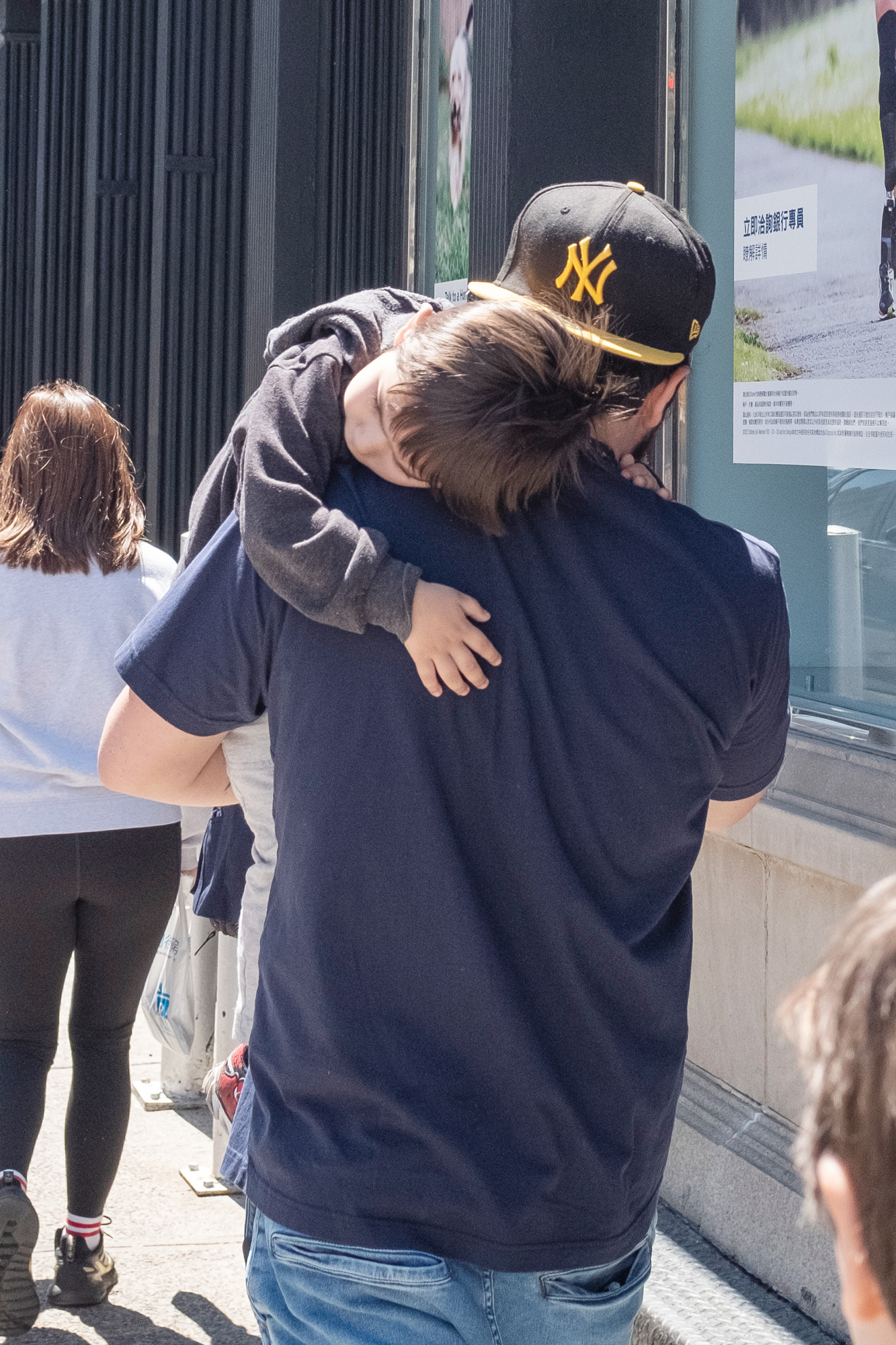 Parent holding sleepy child while walking down the street