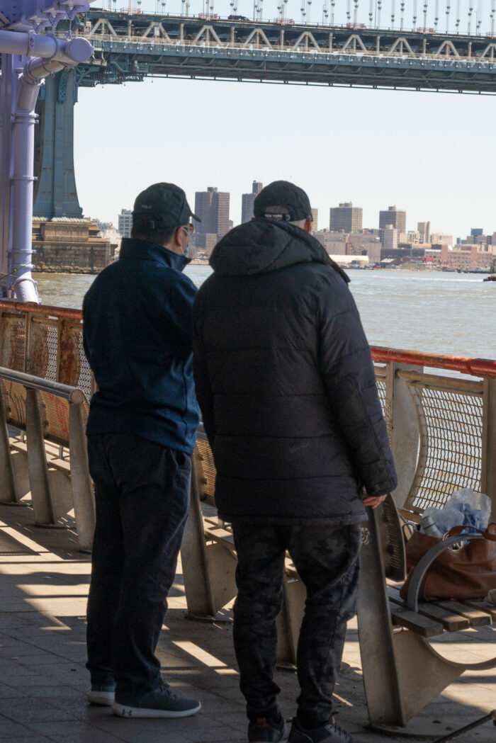 Two men standing in front of the water chatting