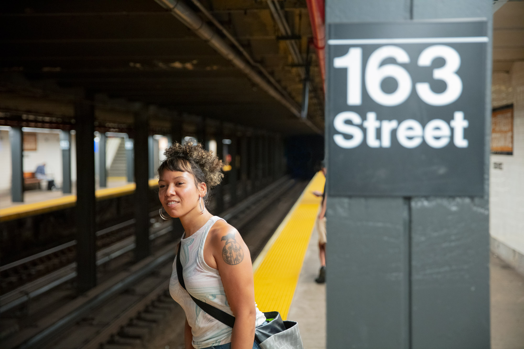 A woman looks down the tunnel as she waits for a train to arrive at the subway station