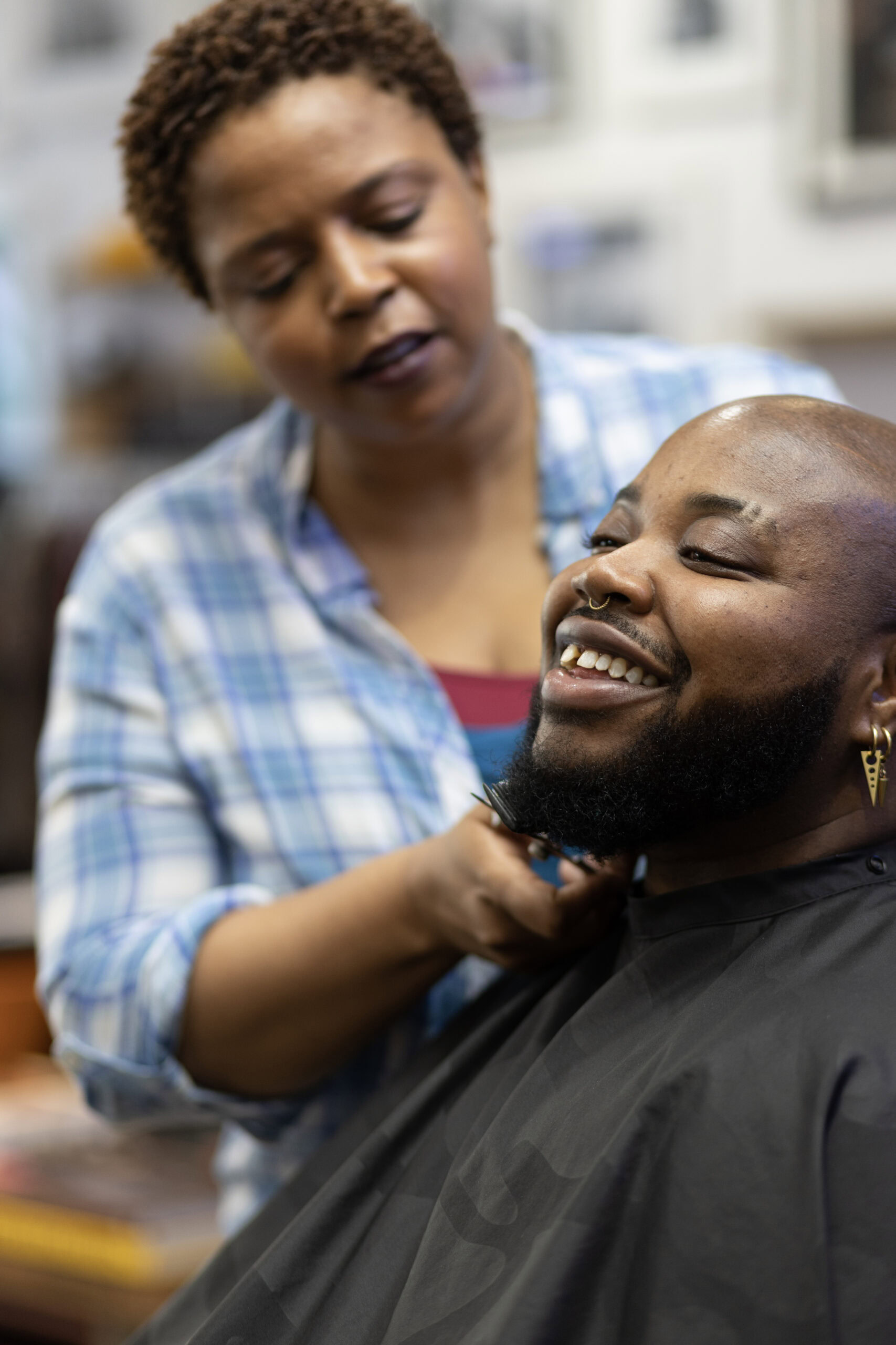 Barber trimming the beard of a smiling man