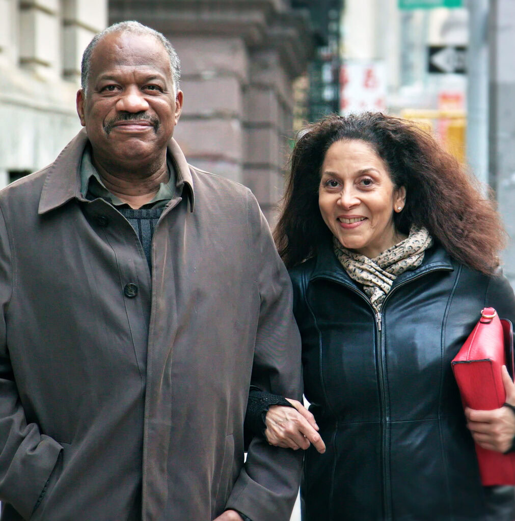 A close up view of a couple linking arms and smiling on a city street