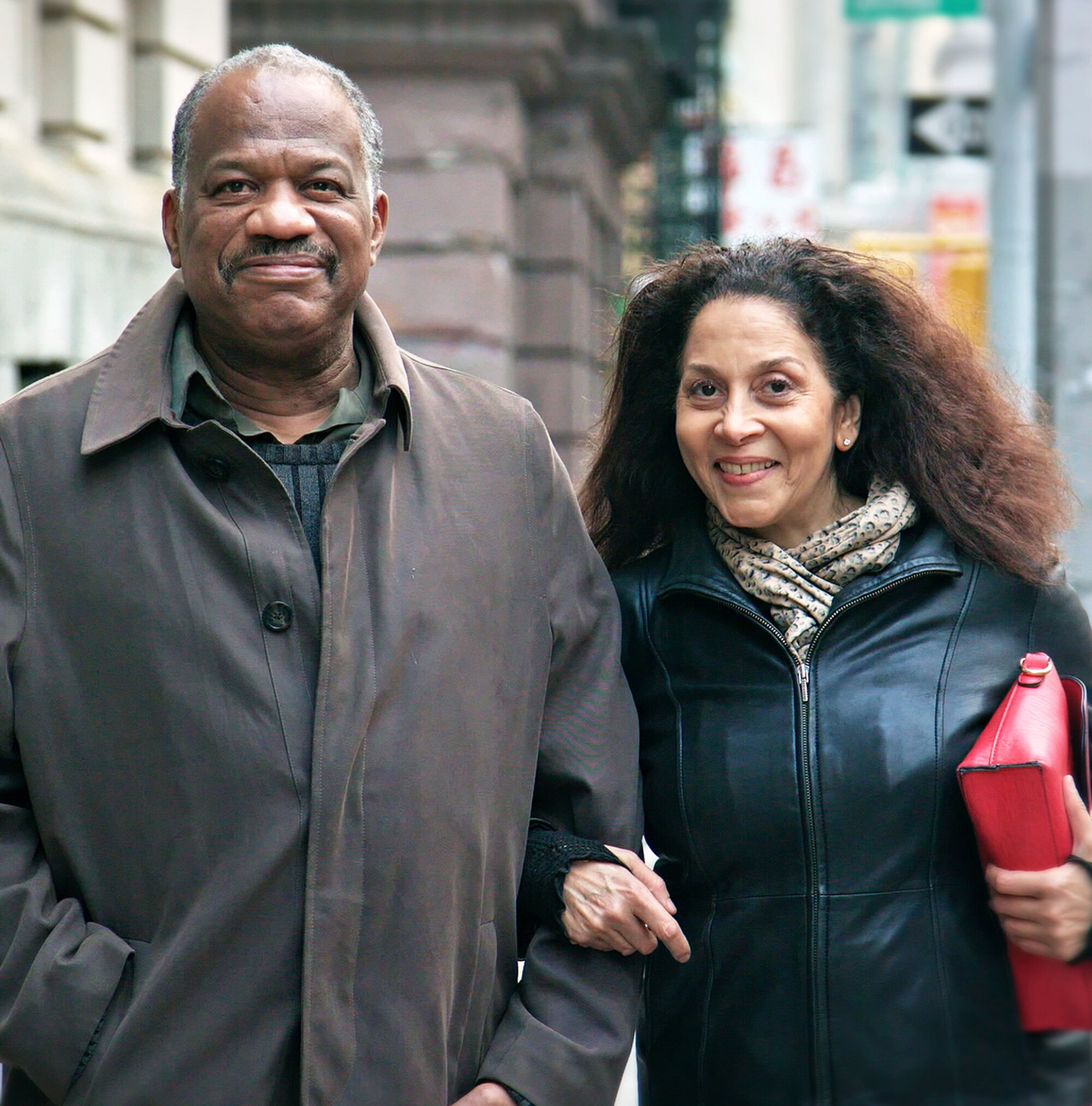 A close up view of a couple linking arms and smiling on a city street