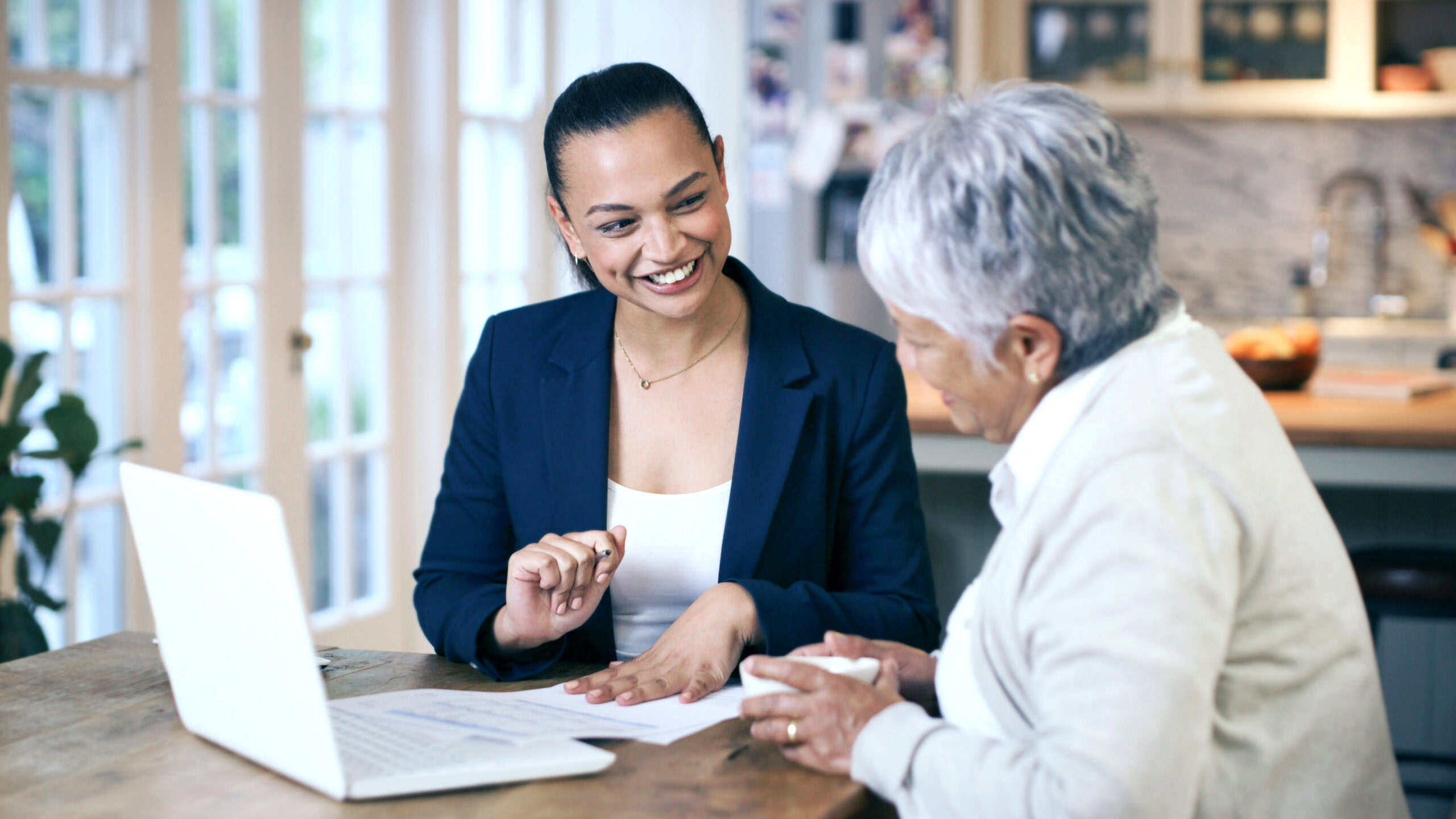 Shot of a consultant going through paperwork during a meeting with a senior woman at home