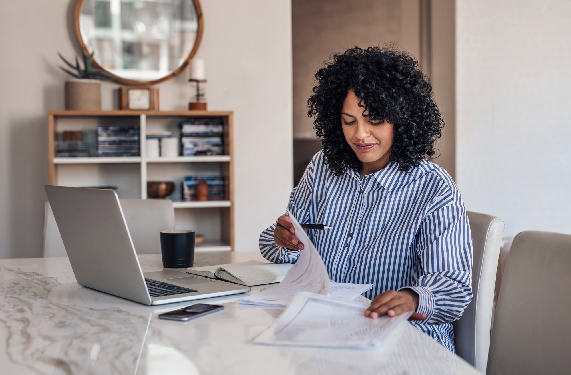 Smiling female entrepreneur going through paperwork at her dining table