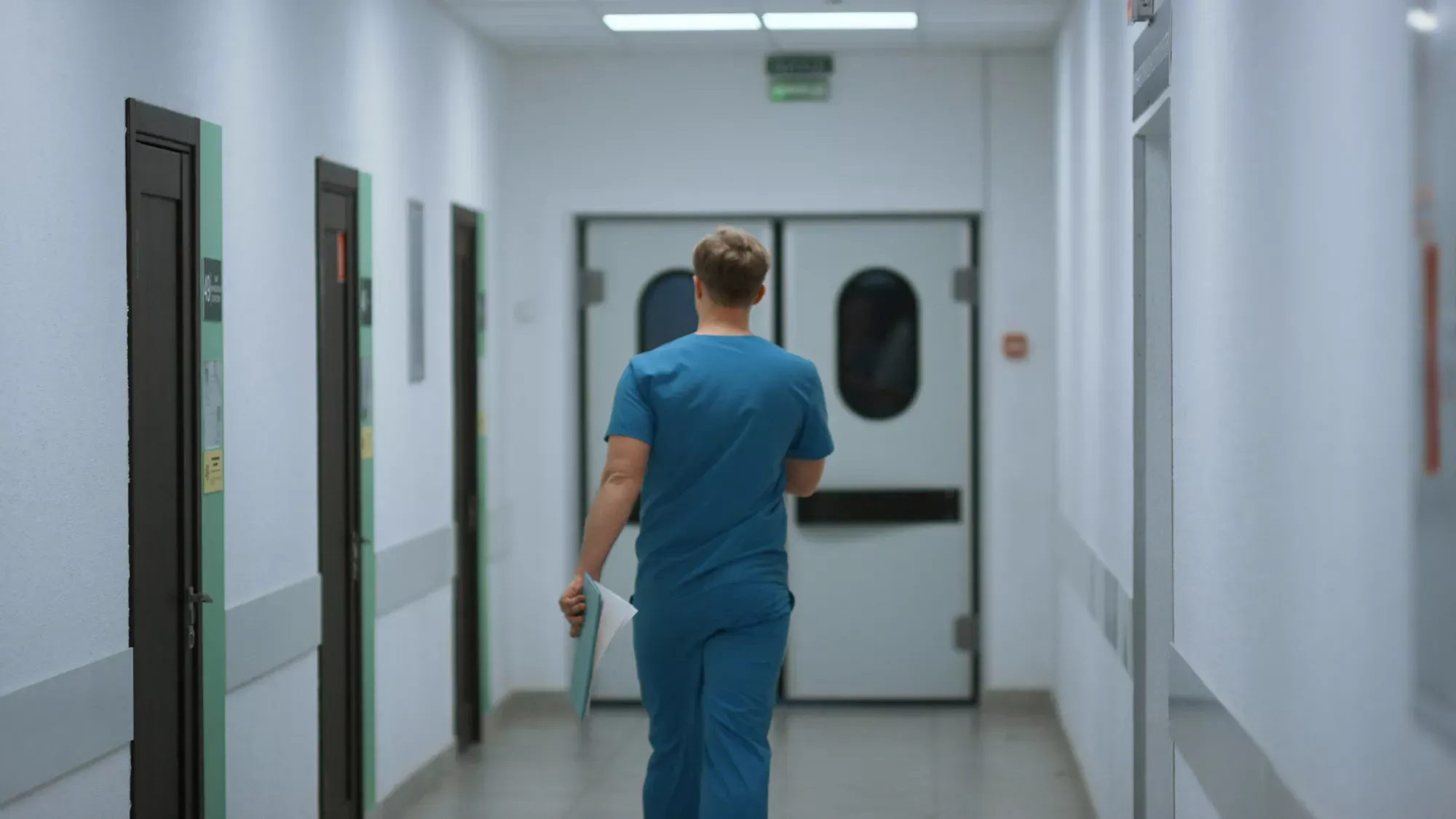Doctor reading MetroPlusHealth provider manual with forms on desk.