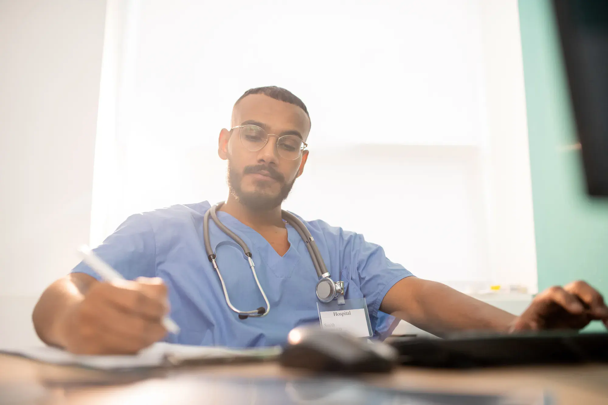 Healthcare provider using a laptop to review MetroPlusHealth forms, manuals, and policy documents.