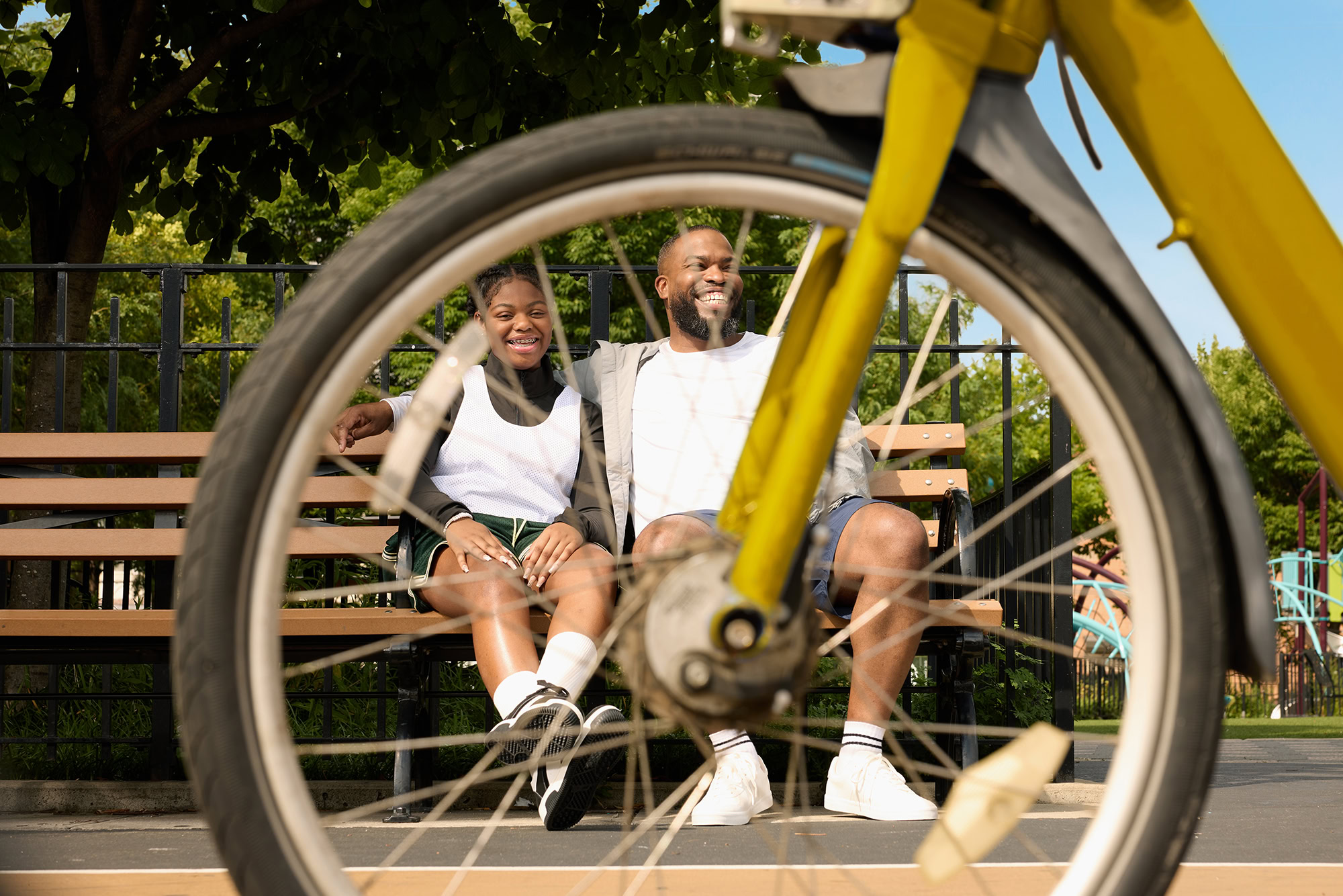 father and daughter sitting on a bench park laughing