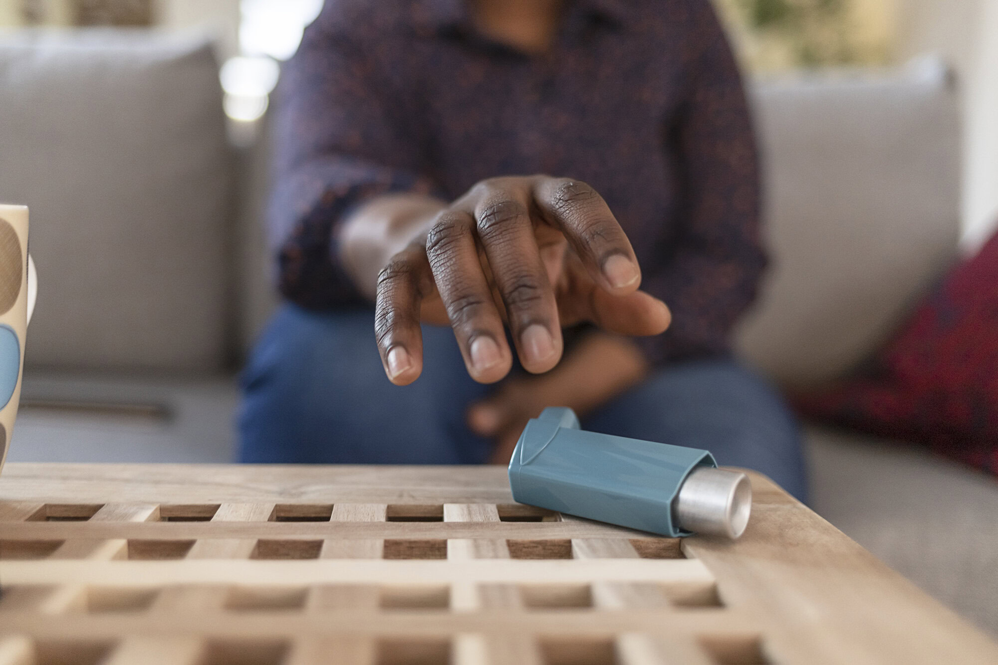 An asthma patient reaching for his inhaler, promoting asthma awareness and management.