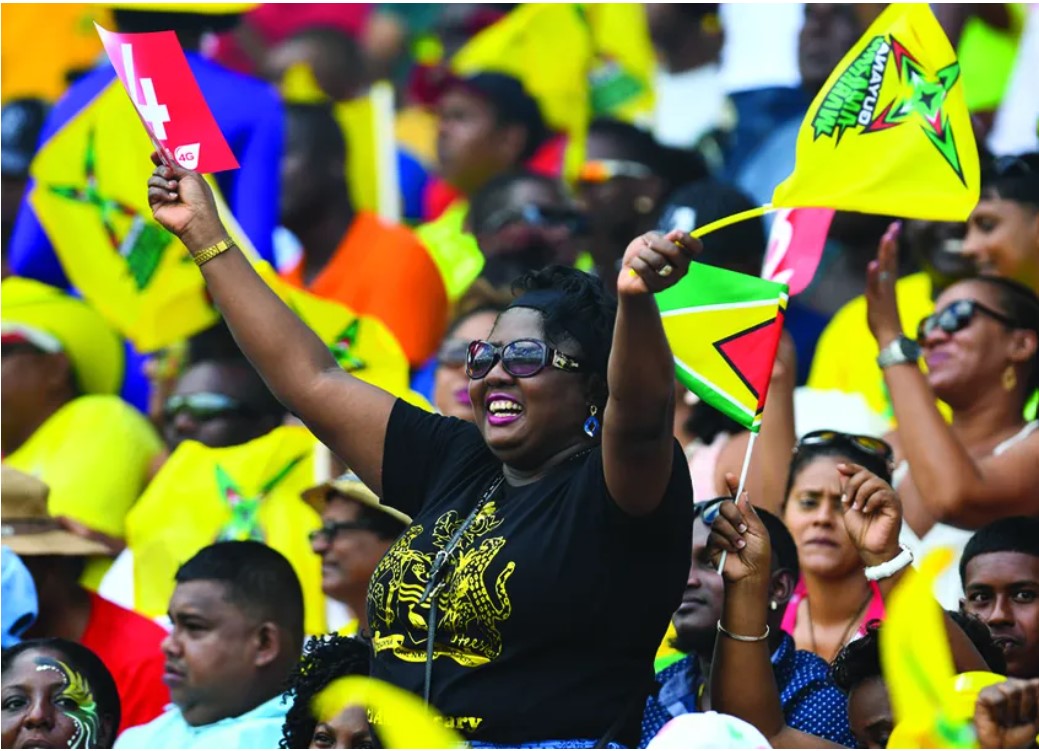 Crowds celebrating their Guyanese heritage amongst vibrant music and dancers at the Guyana Folk Festival in Brooklyn, NY.