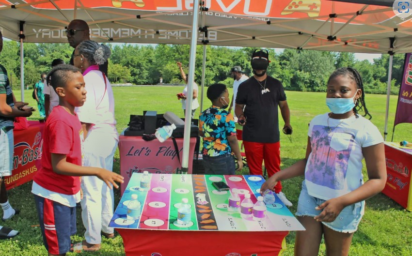 Children participating in traditional Guyanese games at Family Fun Day, surrounded by cheering families.
