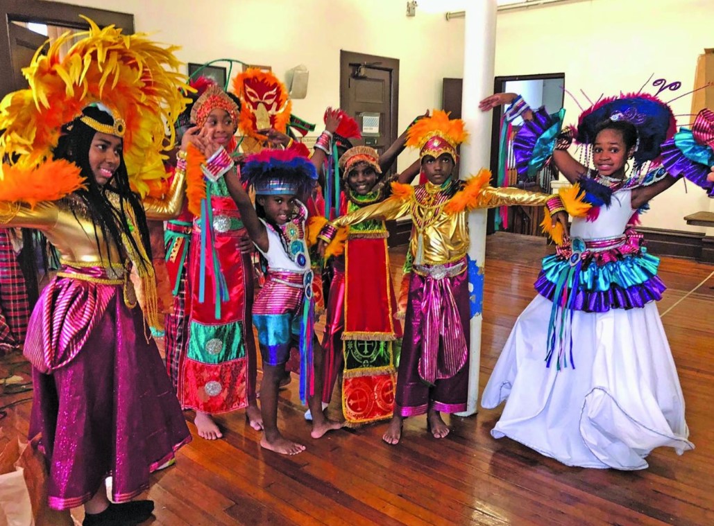 Drummers and dancers leading a Kwe Kwe ceremony, surrounded by a cheering crowd at the Guyana Folk Festival.
