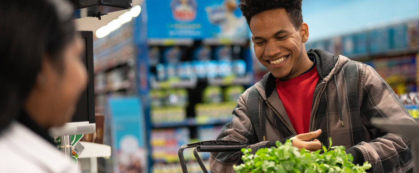 A smiling family shopping for fresh fruits and vegetables at a local grocery store, using their MetroPlusHealth Wellness Card.