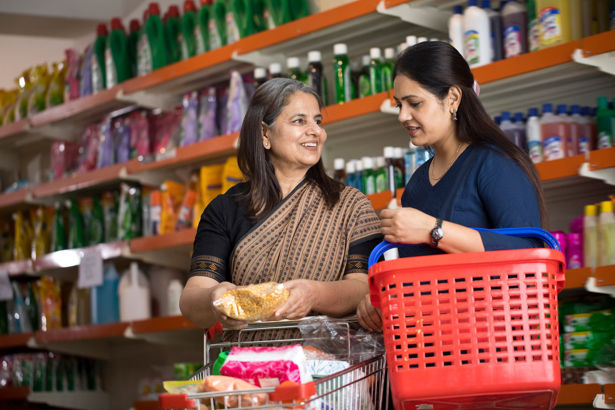 Mother and adult daughter with shopping cart and basket at discount store