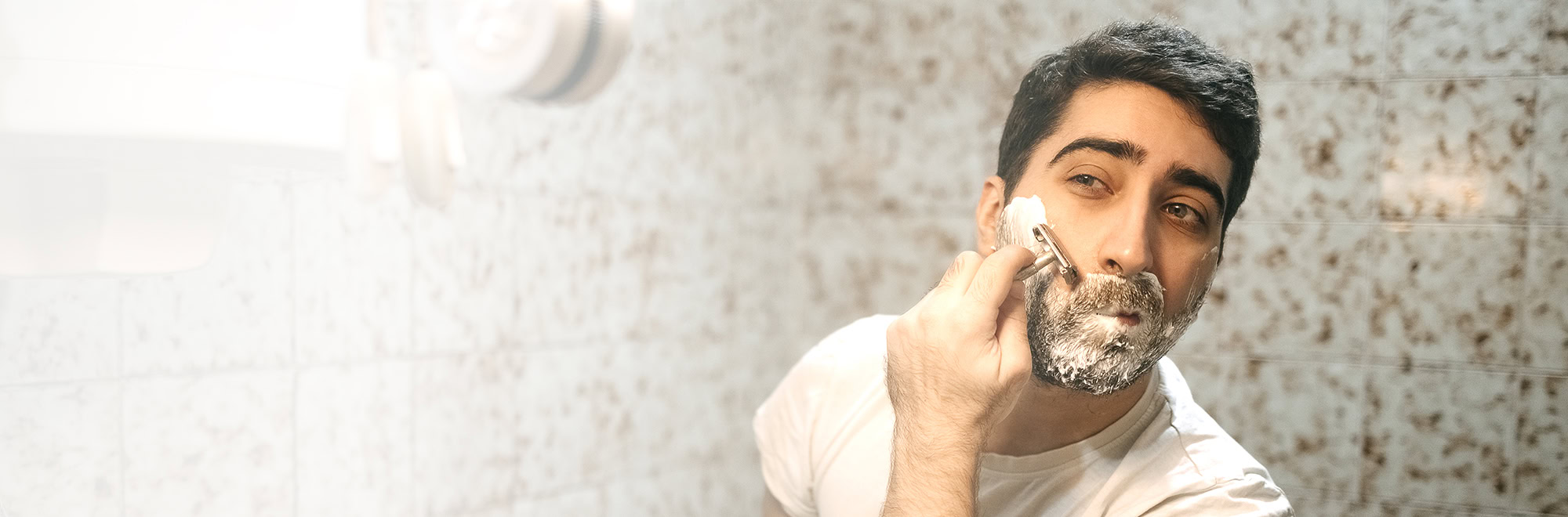 Young man personal care, morning hygiene in the bathroom with shaving beard.