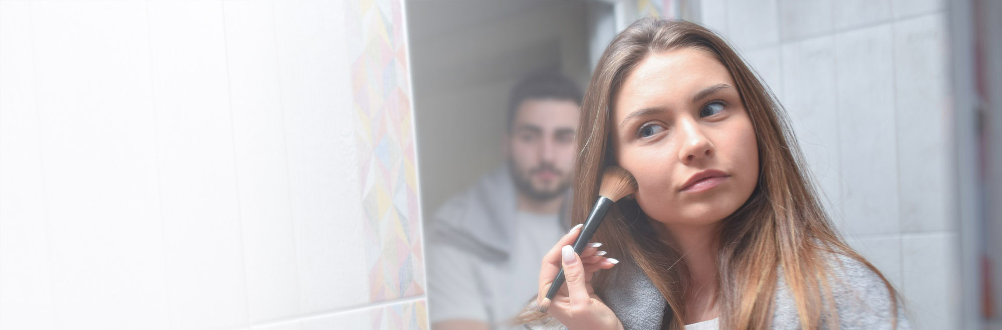 young couple in front mirror in bathroom  apply make-up